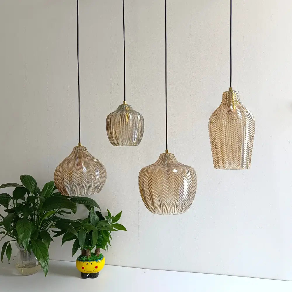 Four gold-toned woven glass pendant lights with black cords in Nordic style for kitchen and dining room lighting