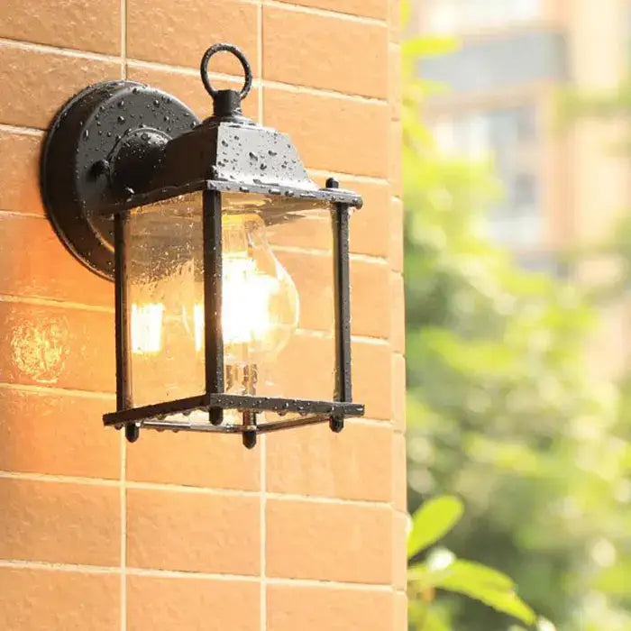 Black finish wrought iron wall lantern with clear glass panels and glowing bulb for outdoor porch lighting decorbites black finish