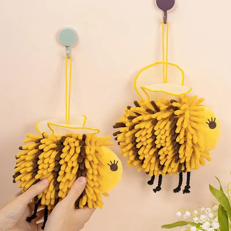 Yellow and black bee shape chenille hand towels in yellow and brown fuzzy design hanging from hooks for bathroom use