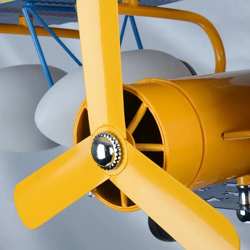 Yellow metal propeller with chrome center hub on vintage-style blue biplane airplane chandelier led lights for boys bedroom