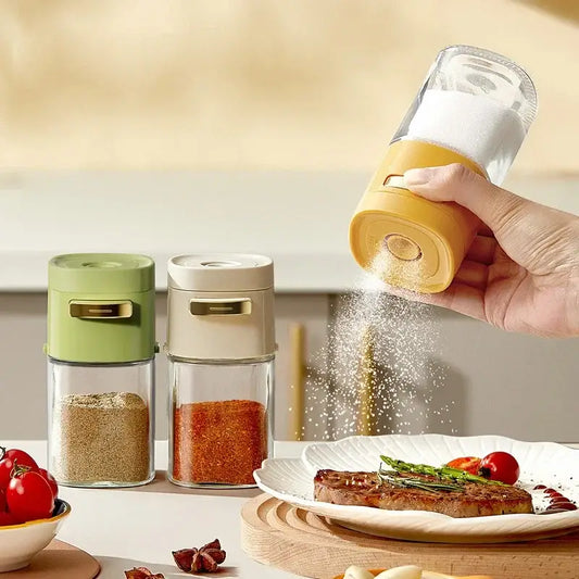 Yellow and clear glass spice dispenser with gold-colored top designed as a kitchen salt grinder