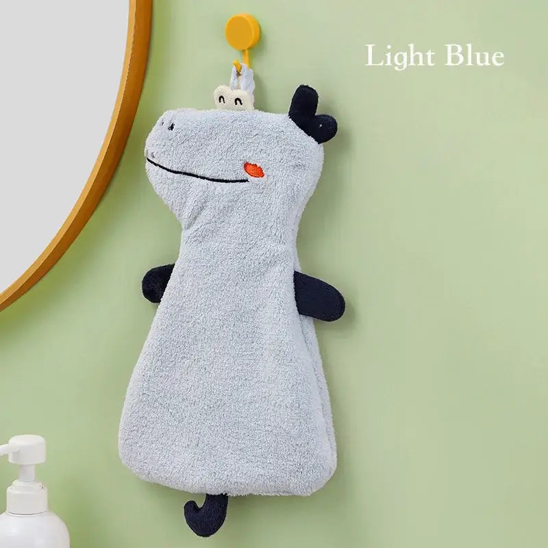 Light blue plush decorbites cartoon animal hand towel with black accents and orange nose hanging from yellow hook