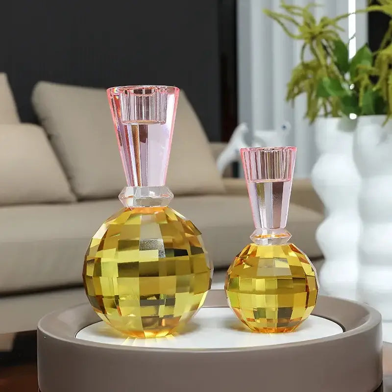 Two faceted crystal candle holders with golden yellow spherical bodies and pink ribbed necks for dining room centerpiece