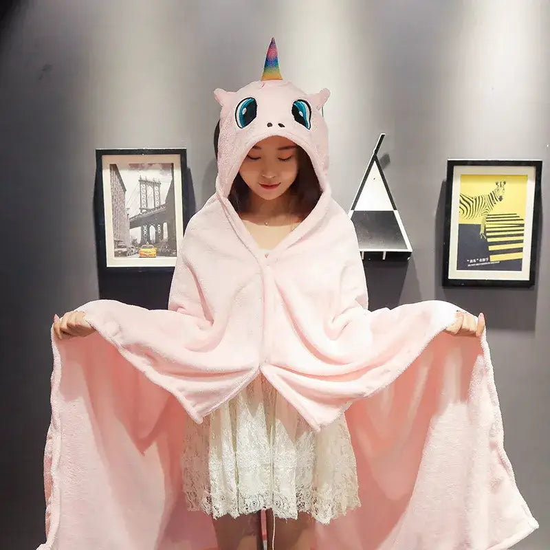 Pink unicorn-themed hooded cape blanket with rainbow horn and blue eyes made of soft plush for bedroom and office warmth