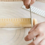 Yellow biscuit cake rolling mold with scale ruler slicing pale yellow rolled dough for decorbites biscuit cake rolling