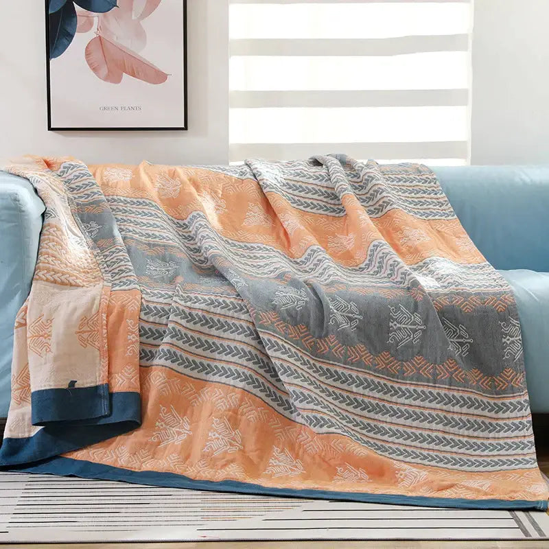 A cozy cotton stripe gauze towel quilt with orange and gray stripes and white geometric designs for summer use