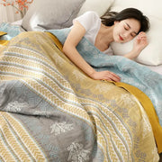 A soft multi-colored cotton stripe gauze towel quilt in yellow gray and blue with a geometric pattern for summer use