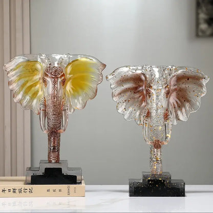 Two translucent yellow and blue decorbites crystal elephant sculptures with golden accents on black marble bases for home decor