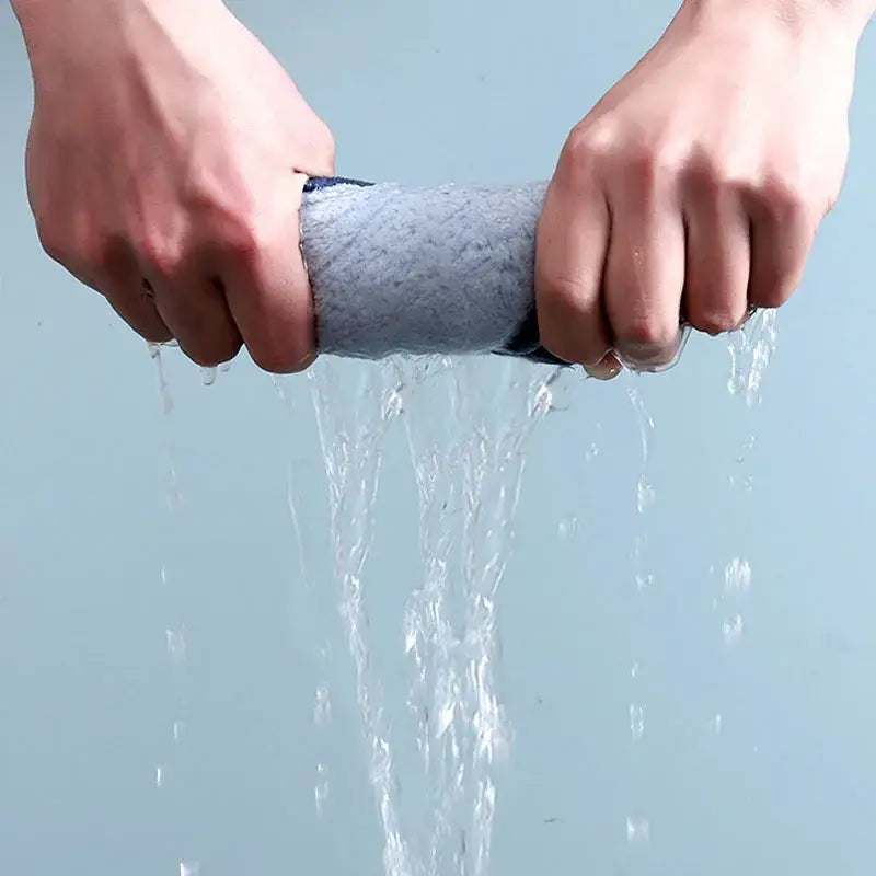 Gray microfiber cleaning cloth being squeezed to show absorbency with yellow decorbites cartoon pig plush hand towel nearby