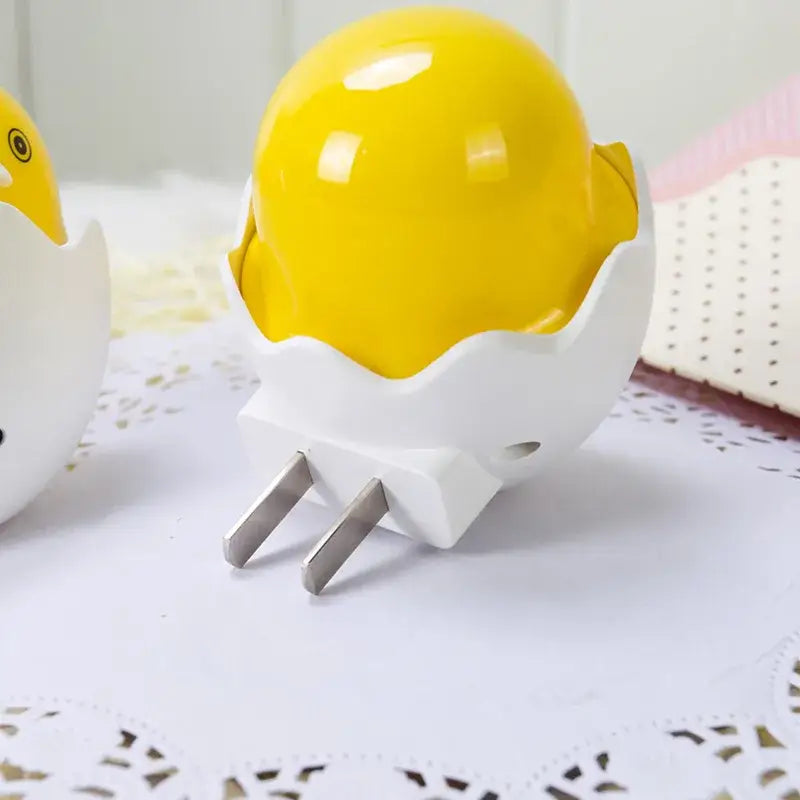 Bright yellow ceramic chick-shaped led night light with white eggshell base and metallic plug for bedroom use