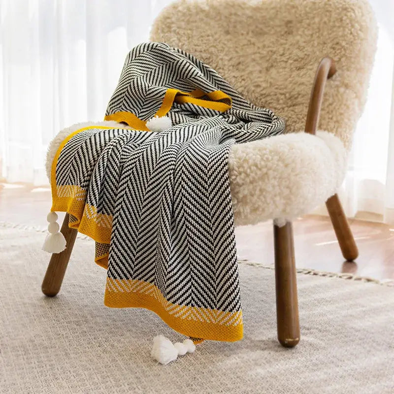 A cozy black and yellow herringbone knit sofa blanket with tassels featuring diagonal stripe decorbites knitted diagonal design