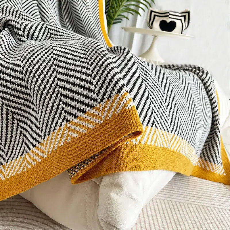 A cozy knitted sofa blanket with diagonal stripe black and white herringbone pattern and yellow edge decorbites knitted diagonal