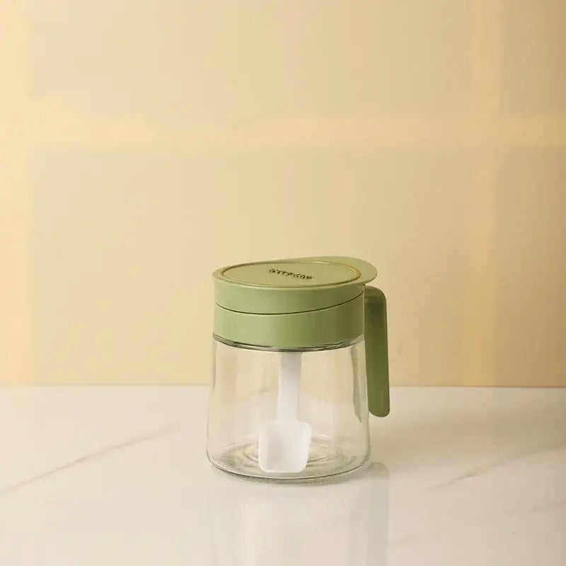 Yellow flip top glass seasoning jar with sage green lid and integrated white spoon for kitchen spice use