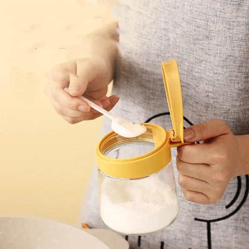 Yellow flip top glass seasoning jar with bright yellow lid and integrated spoon for easy portioning of spices