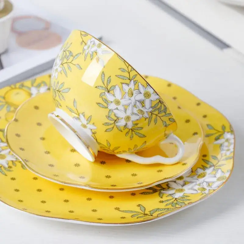 A vibrant yellow lemon tree bone china teacup with white and green floral patterns on a matching saucer decorbites lemon tree