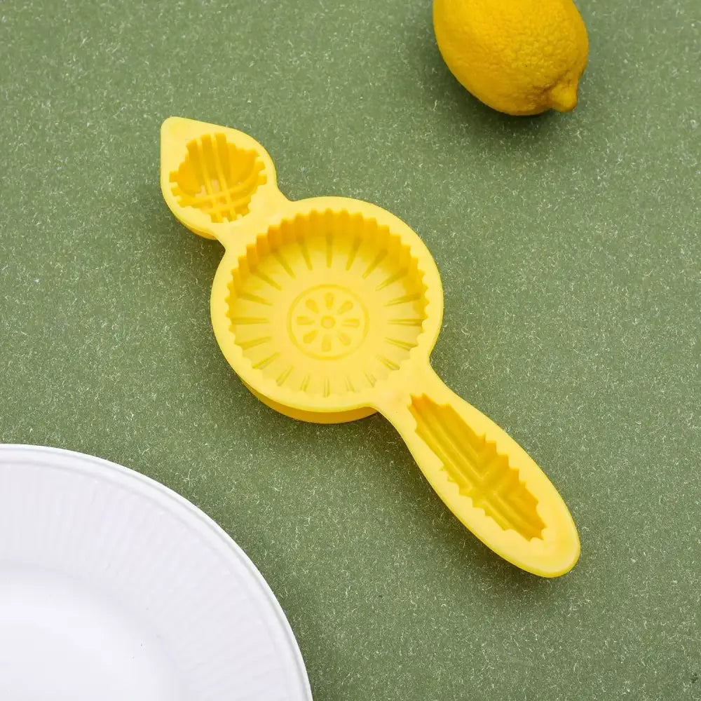 Bright yellow silicone lemon squeezer with sunburst pattern and leaf handles ideal for decorbites biscuit cake date pistachio use