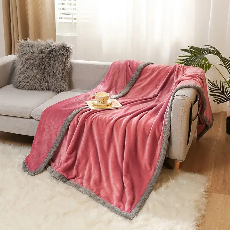 Pink plush throw blanket with gray textured border draped over sofa featuring decorbites cartoon flannel design