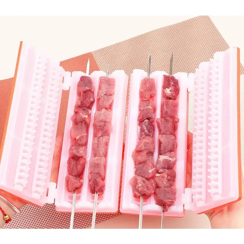 Pink plastic bbq meat skewer maker with four compartments holding raw meat pieces on metal skewers for kebabs