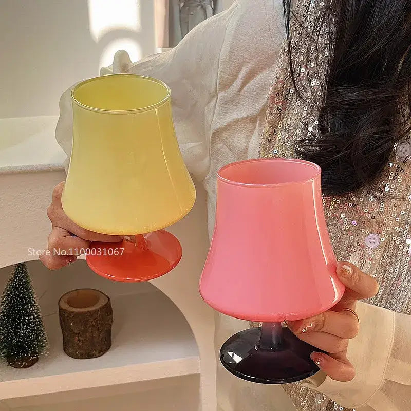 Two translucent gem champagne coupe glasses with yellow lime green and pink dark purple stems held in hands