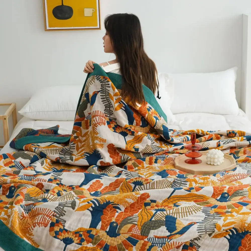 A cozy cotton gauze soft throw blanket with vibrant orange blue and teal botanical print on white decorbites cotton gauze