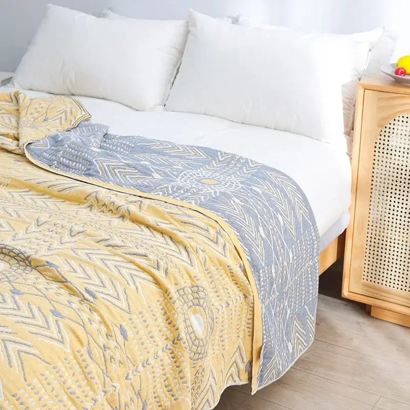 Yellow navy and white cotton gauze soft throw blanket with yellow and gray geometric design draped over bed decorbites cotton gauze