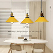 Three bright yellow conical pendant lights with brass fixtures decorate a dining room in decorbites colorful nordic style