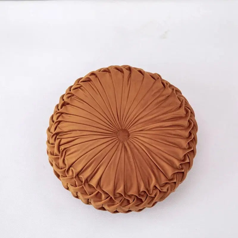 A rust-colored round throw pillow with pleated velvet fabric perfect for decorbites 3d pumpkin style decor