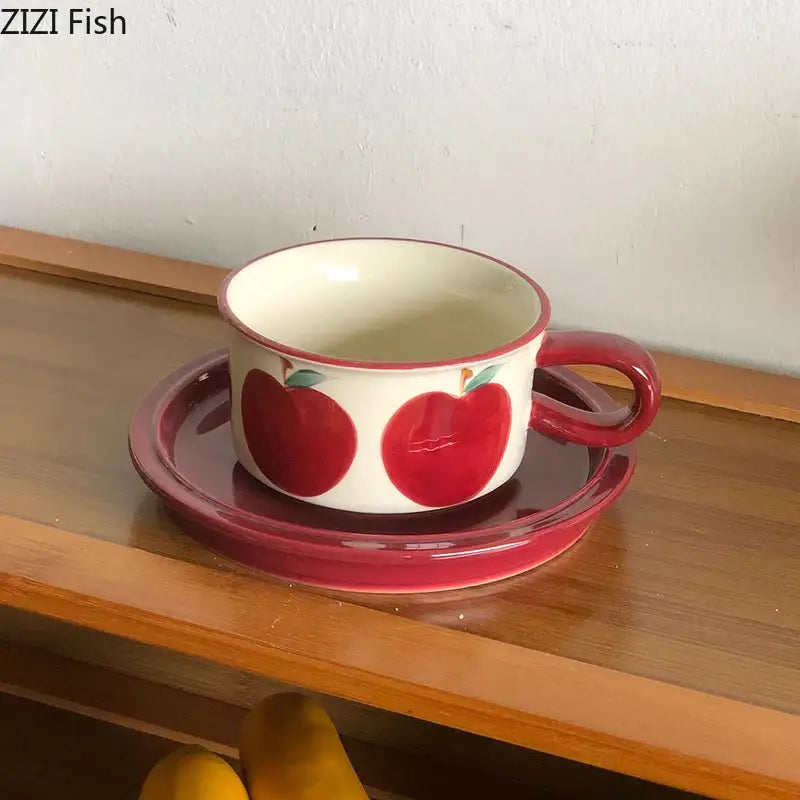 A white fruits pattern porcelain coffee mug with red apple decorbites on a matching glossy red saucer