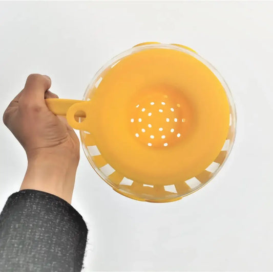 Yellow silicone colander with clear plastic rim and perforated base for glass popcorn maker kitchen use