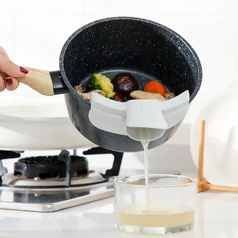 White silicone pot strainer attached to black speckled pan showcasing decorbites duck beak funnel design
