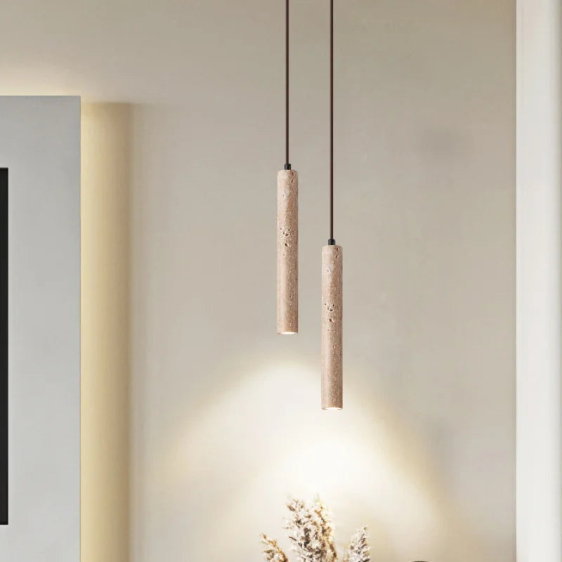 Two minimalist beige stone pendant lights with textured concrete cylindrical shades for bedroom lighting