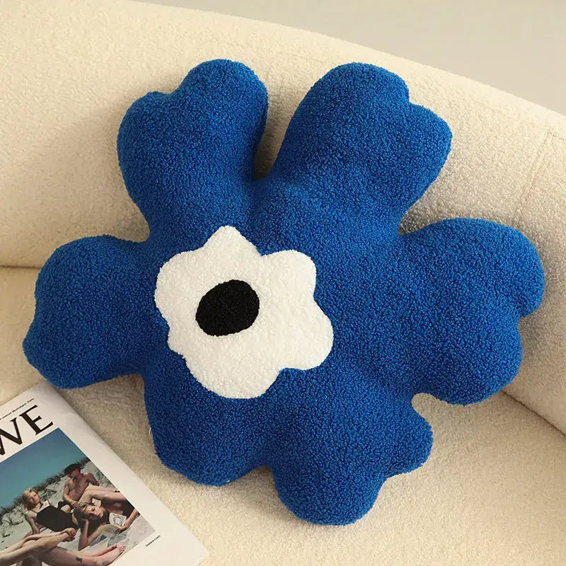 A plush royal blue decorbites 3d flower shaped decorative throw pillow with a white and black center for living room decor