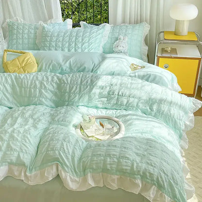 Mint green quilted duvet cover set with white ruffled edges and matching pillows in yellow and white bubble gauze cover set