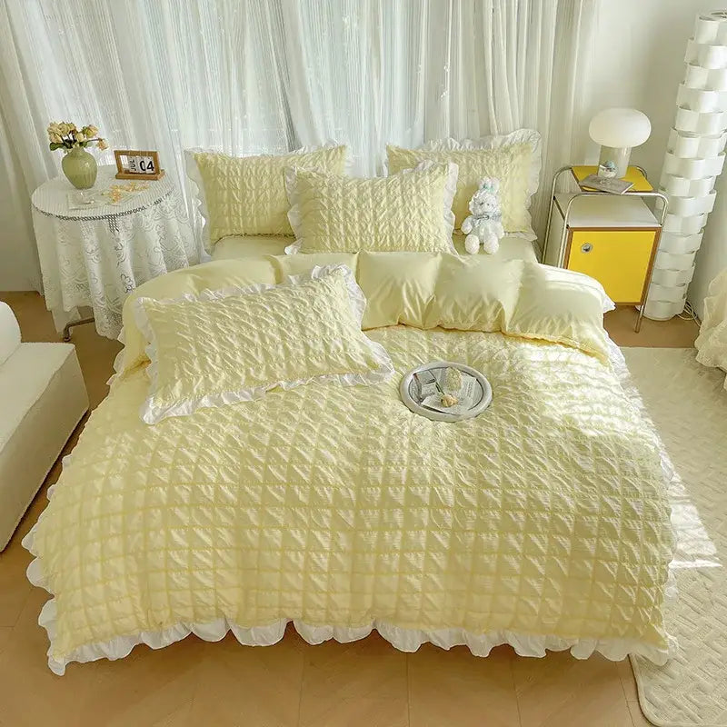 Soft pale yellow quilted duvet cover set with delicate white ruffled trim and matching pillows for bedroom bedding