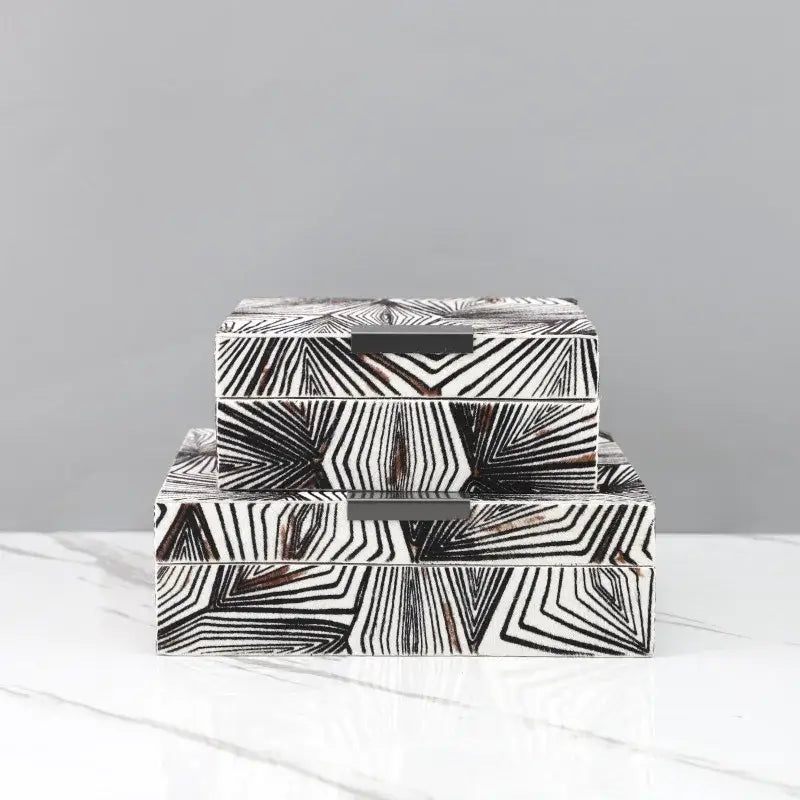 Stacked zebra black and white geometric jewelry storage box with dark metal handles for desktop organization