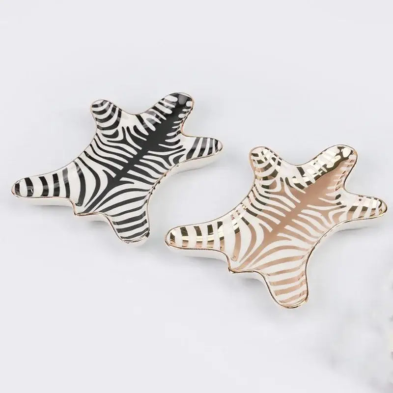 Two star-shaped ceramic jewelry holder trays with black white zebra stripes and gold tiger skin metallic edges