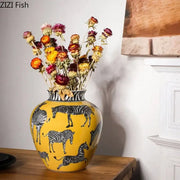 A vibrant yellow ceramic zebra yellow vase with black and white zebra patterns and artificial flowers for desk decoration