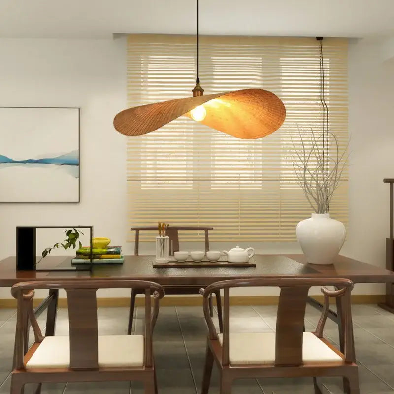 A warm bamboo zen tea chandelier with woven shade and brass hardware hangs above a tea room dining table