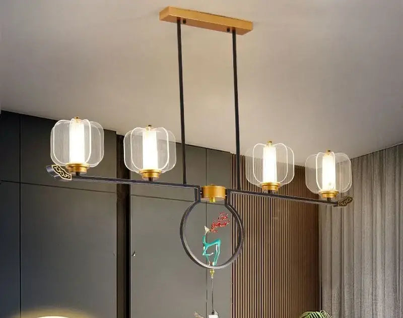 Modern pendant light with four clear glass lanterns, gold metal accents, and ornate decorbites deer enamel design
