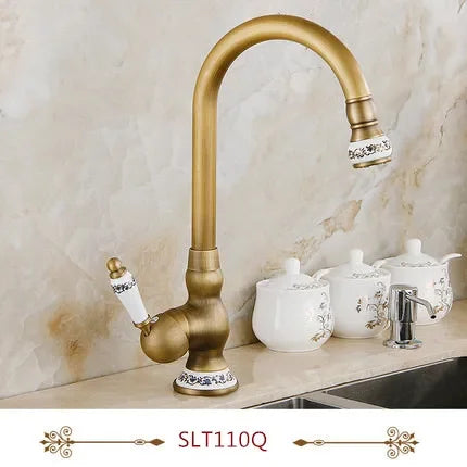 Gold-toned deck mounted single hole kitchen faucet with curved spout and porcelain accents in antique brass housing material