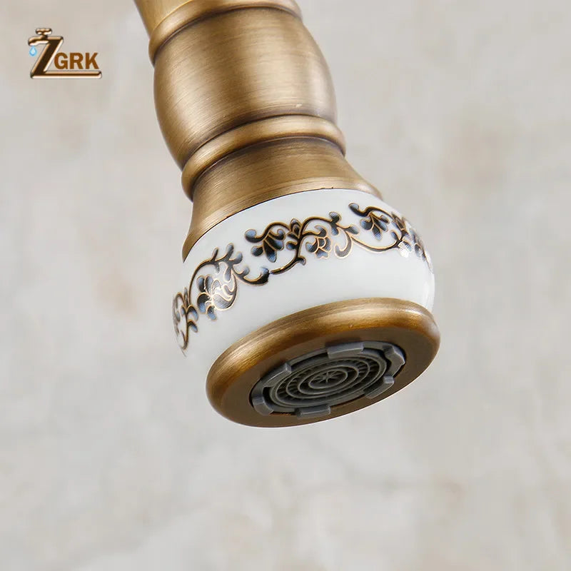 Antique brass single hole mixer tap with white ceramic accent and black gold floral detailing for kitchen sink